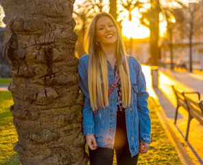 Lifestyle, young blonde smiling in a tree with a cowgirl jacket on a sunset