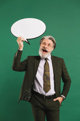 Business middle-aged bearded man in khaki suit holding emoji with copy space on a green background