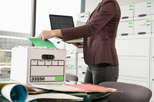 Tight shot of a woman holding a laptop sorting through a box., Jacksonville, Florida, USA