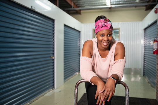 Portrait of a woman leaning over a cart inside a storage facility., Jacksonville, Florida, USA