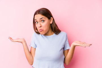 Young caucasian woman wearing a ski clothes isolated doubting and shrugging shoulders in questioning gesture.