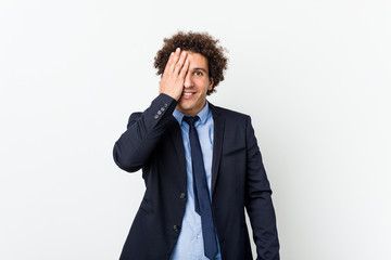 Young business curly man against white background having fun covering half of face with palm.