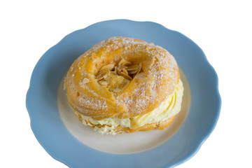 Sprinkle puff rings with curd cream with powdered sugar on a blue plate. Isolated on a white background.