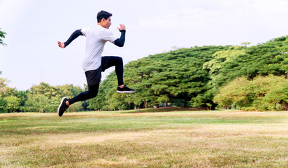 Fototapeta na wymiar Handsome young man athlete runner with energy exercise training and jumping outdoors with big green tree in the public park. Active healthy and motivation lifestyle and ambition Concept