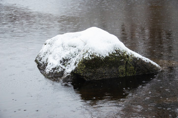 A snow covered rock in a winter lake