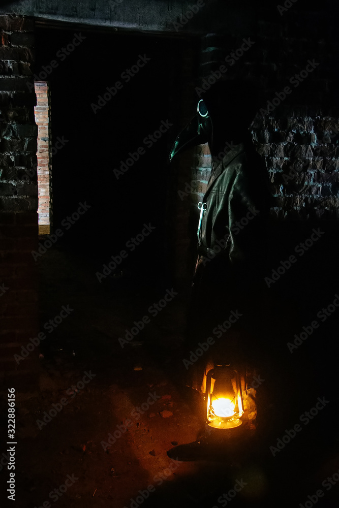 Wall mural Terrible plague doctor with kerosene lamp. Masked maniac. Halloween and horror concept - Wall murals