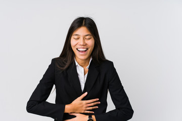 Young asian business woman laughs happily and has fun keeping hands on stomach.