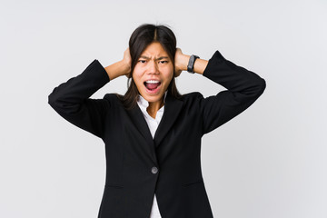 Young asian business woman covering ears with hands trying not to hear too loud sound.