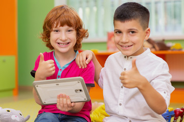 Two little boys using dicital tablet at kindergarten