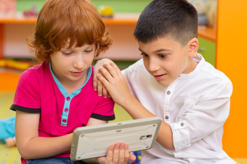 Two little boys using dicital tablet at kindergarten
