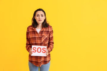 Young woman holding paper with text SOS on color background. PMS concept