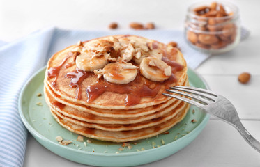 Plate with stack of tasty pancakes on table