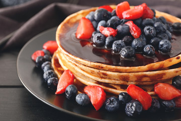 Plate with stack of tasty pancakes on table
