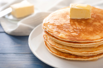 Plate with stack of tasty pancakes on table