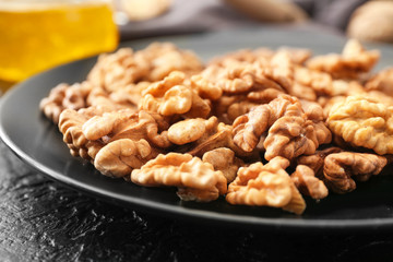 Plate with tasty walnuts on table, closeup