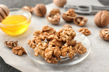 Plate with tasty walnuts and honey on table