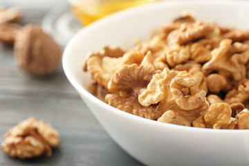 Bowl with tasty walnuts on table, closeup