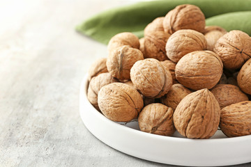 Plate with tasty walnuts on table
