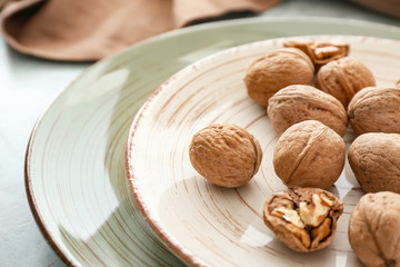 Plate with tasty walnuts on table, closeup