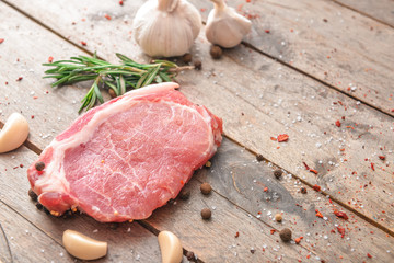 Raw pork meat with spices on wooden background