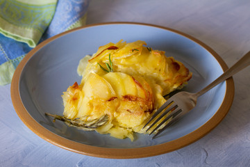 Potato gratin on blue plate. Scalloped potatoes or potato bake. horizontal image