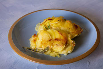 Potato gratin on blue plate. Scalloped potatoes or potato bake. horizontal image