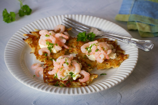 Potato cakes with topping: cream cheese and shrimps on white plate. Vegetable fritters, pancakes. Horizontal image