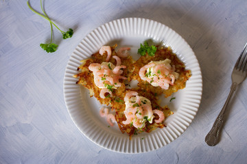 Potato cakes with topping: cream cheese and shrimps on white plate. Vegetable fritters, pancakes. Overhead horizontal image
