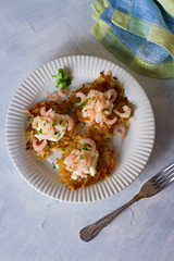 Potato cakes with topping: cream cheese and shrimps on white plate. Vegetable fritters, pancakes. Overhead vertical image