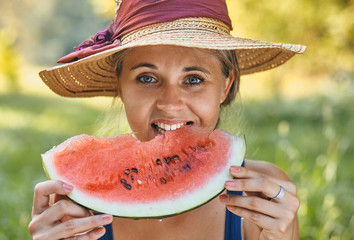 beautiful woman eating watermelon in summer in park