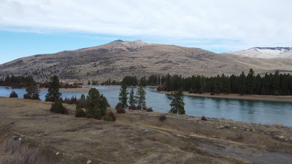 Large river flowing around an island surrounded by trees and rolling grass hills © Richard