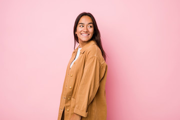 Young mixed race indian woman isolated looks aside smiling, cheerful and pleasant.