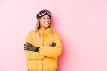 Young caucasian woman wearing a ski clothes in a pink background smiling confident with crossed arms.