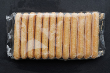 Italian savoiardi biscuits finger biscuits in the package. Black background.