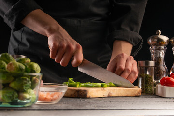 The chef prepares a salad with vegetables, cut vegetables. Healthy and tasty nutrition. Tasty and healthy food. Cooking and home recipes. Restaurant and hotel business.