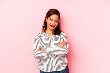 Fototapeta premium Middle age latin woman isolated on a pink background who feels confident, crossing arms with determination.