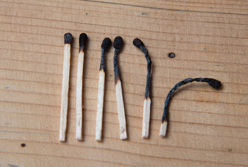 Concept of patience. A row of burnt matches, from left to right, from almost a whole match to a completely burnt match to the dust. wooden background, flat lay.
