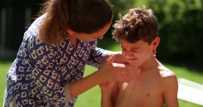 Mother applying sunscreen to child son outdoors. Parent applies sunblock to kid face. Mom caring for offspring