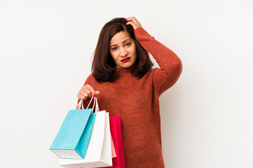 Middle age latin woman holding a shopping bags isolated being shocked, she has remembered important meeting.