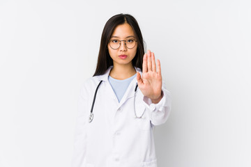 Young doctor chinese woman isolated standing with outstretched hand showing stop sign, preventing you.