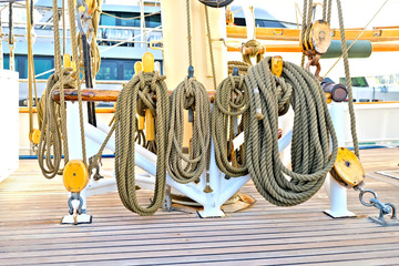 Hempen lines neatly coiled on a beautiful vintage classic sailing ship. Beautiful teak planks of...