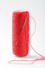 Spool of red thread and needle macro photography