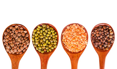 Collection of various lentils in a wooden spoons isolated on a white background. Top view.