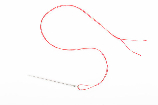 Sewing needle with red thread on the white background	