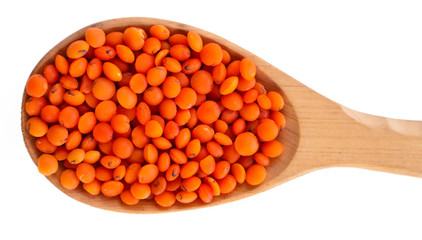 Red lentils in the wooden spoon isolated on a white background. Top view.