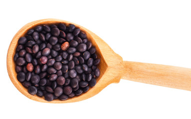 Black lentils in the wooden spoon isolated on a white background. Top view.