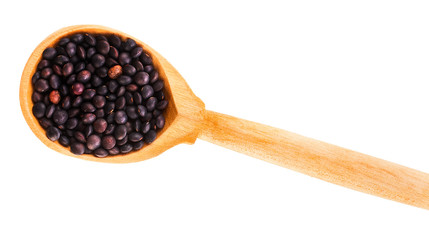 Black lentils in the wooden spoon isolated on a white background. Top view.