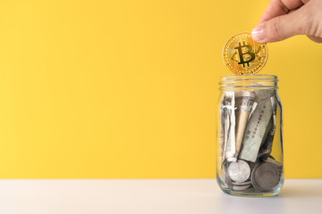 Hand drop gold Bitcoin the jar full of coin and bank notes meaning of saving investment with...