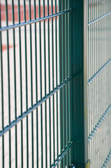 The metal fence is green. Fence close-up. Fenced territory.