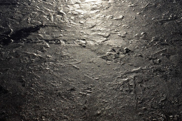Ice surface color: black, gray, white. The glint of sunlight on black ice.